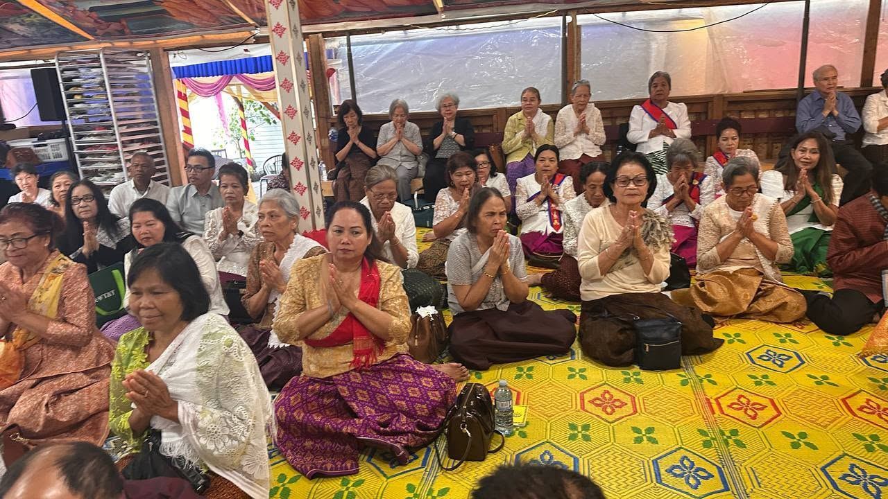 Women praying with their hands together on yellow woven mats