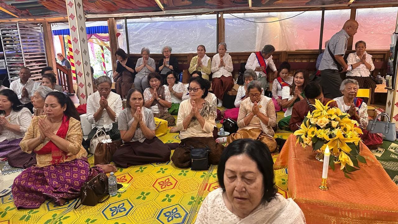 Elders praying with their hands together on woven mats in the festival tent